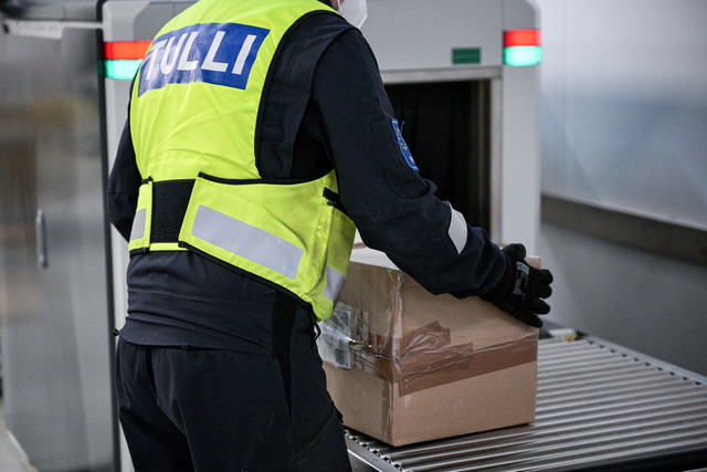 Tullin työntekijä tutkii pakettia, joka tulee läpivalaisusta.