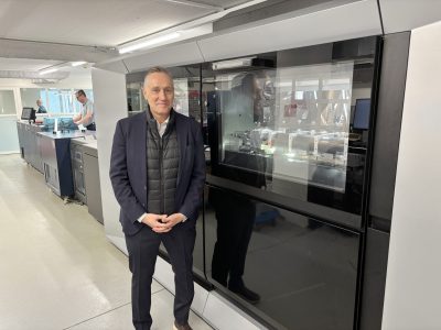 Mies seisoo modernin painokoneen vieressä.